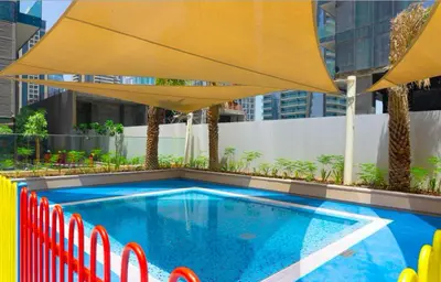 a swimming pool with a large yellow umbrella at StoneTree - Marina Gate 2 BR - Prime location in Dubai