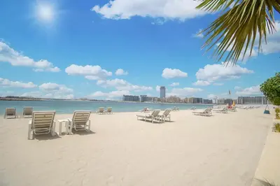 a sandy beach with chairs and the ocean on it at Vacay Lettings - Private Beach Access -Emaar Beachfront in Dubai