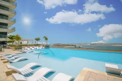 a large swimming pool with white lounge chairs at Vacay Lettings - Private Beach Access -Emaar Beachfront in Dubai