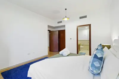 a bedroom with a white bed and a blue rug at Contemporary & Roomy 2BR with Burj Khalifa view in Dubai