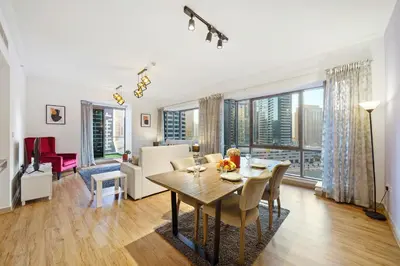 a dining room with a table and chairs and a living room at Contemporary & Roomy 2BR with Burj Khalifa view in Dubai