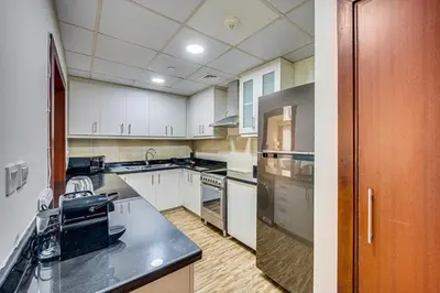 a kitchen with white cabinets and a black counter top at New sea view Rimal 2BD in front of the beach in Dubai