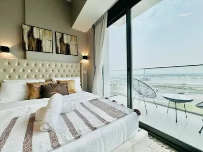 a bedroom with a white bed and a large window at Venduras - Skyline View Farhad Azizi Residence Al Jaddaf in Dubai