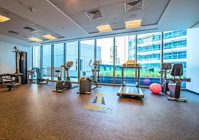 a gym with exercise equipment in a building with windows at One Bed in Dubai Marina with Marina Views, Hosted by Desert City Stays in Dubai