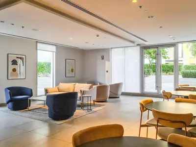 a living room with chairs and tables and windows at Incredible Waterfront Apt with Panoramic Views in Dubai