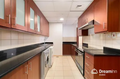a large kitchen with wooden cabinets and a washer and dryer at Dream Inn Apartments - Sadaf Residence JBR in Dubai