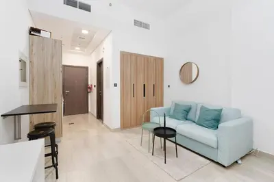 a living room with a blue couch and a table at Nice and cozy Studio Elysée 2 in JVC - Dubai in Dubai