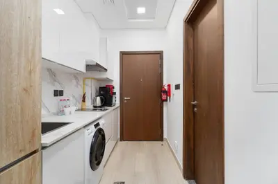 a kitchen with a washer and a wooden door at Nice and cozy Studio Elysée 2 in JVC - Dubai in Dubai