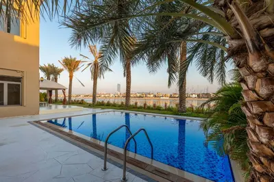 a swimming pool with palm trees next to a building at Maison Privee - Exclusive Villa with Private Pool, Garden & Beach in Dubai