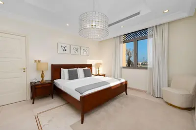 a bedroom with a bed and a chair and a window at Maison Privee - Exclusive Villa with Private Pool, Garden & Beach in Dubai