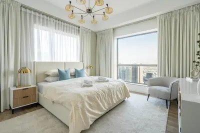 a bedroom with a bed and a chair and a window at GuestReady - Modern and luxe near JBR Beach in Dubai