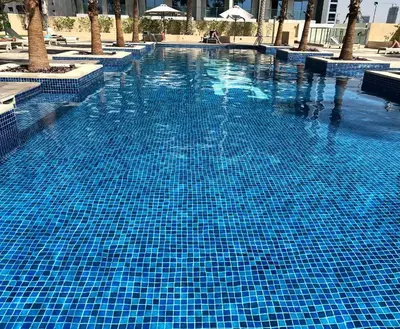 a swimming pool with blue tiles in a resort at Lux BnB Studio Ghalia JVC in Dubai