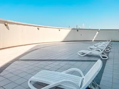 a row of white chairs sitting on a roof at Cosmos Living Cozy Studio Near Dubai Marina in Dubai