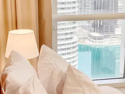 a bed with white pillows and a window with a view at Cosmos Living Cozy Studio Near Dubai Marina in Dubai