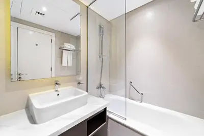 a white bathroom with a sink and a shower at ALiving Modern Studio I Canal View I DAMAC Maison Prive A- 1102 in Dubai