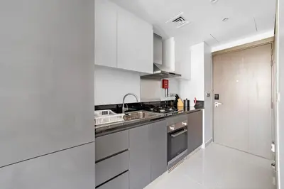 a kitchen with white cabinets and a sink at ALiving Modern Studio I Canal View I DAMAC Maison Prive A- 1102 in Dubai