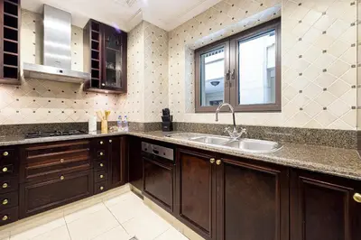 a kitchen with wooden cabinets and a sink at Luxurious Unique 2 Bed with Private Jacuzzi & Garden - Connected to Souk Al Bahar - Dubai Mall in Dubai
