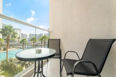 a balcony with a table and chairs and a pool at ALiving Cozy & Modern Studio I DAMAC Maison Prive, Business Bay -302 in Dubai