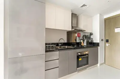 a kitchen with white cabinets and stainless steel appliances at ALiving Cozy & Modern Studio I DAMAC Maison Prive, Business Bay -302 in Dubai