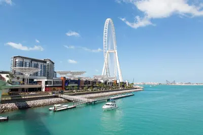a white boat in the water next to a ferris wheel at Frank Porter - The Jwls T2 in Dubai