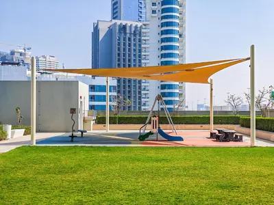 a playground with a canopy in a park with tall buildings at Gorgeous 1 BR with Private Terrace - Marina View in Dubai