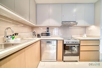 a kitchen with white cabinets and stainless steel appliances at Classic 1BR at Harbour Views Tower 1 by Deluxe Holiday Homes in Dubai