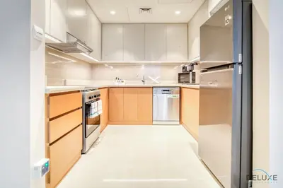 a large kitchen with wooden cabinets and stainless steel appliances at Alluring 1BR at Harbour Views Tower 1 by Deluxe Holiday Homes in Dubai