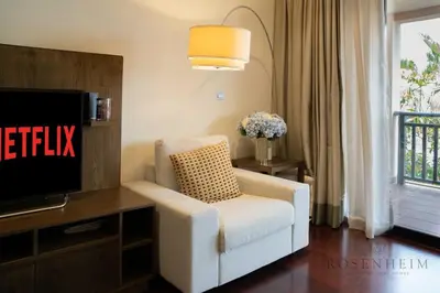 a living room with a white chair and a tv at Luxury Anantara Res - Sea & Burj AlArab View in Dubai