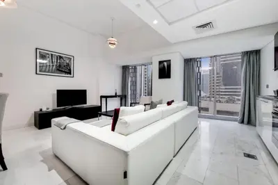 a white living room with a white couch and a tv at Cayan Tower, Dubai Marina - Charming One Bedroom in Dubai
