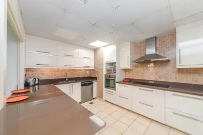 a kitchen with white cabinets and a stainless steel counter top at Elan Rimal Suites JBR Beach Sea View in Dubai