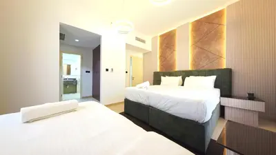 a hotel room with two beds and a bathroom at Elan Rimal Suites JBR Beach Sea View in Dubai
