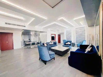 a living room with blue chairs and a couch at Elan Rimal Suites JBR Beach Sea View in Dubai