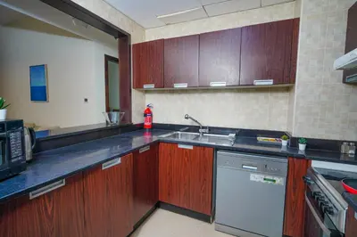 a kitchen with wooden cabinets and a sink and a dishwasher at Unique 1BR Apartment in Sport City in Dubai