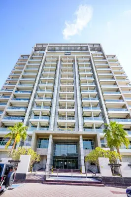 a tall white building with palm trees in front of it at Unique 1BR Apartment in Sport City in Dubai