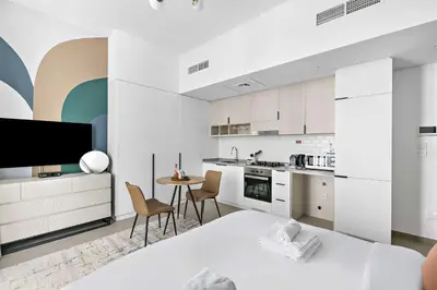 a kitchen with white cabinets and a table and chairs at Silkhaus brand new studio in Belgravia Heights, JVC in Dubai