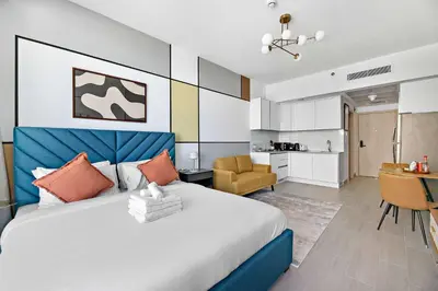 a bedroom with a large bed and a kitchen at Silkhaus new stylish studio in JVC Luma21 in Dubai
