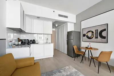 a kitchen and living room with a table and chairs at Silkhaus new stylish studio in JVC Luma21 in Dubai