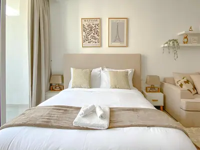 a bedroom with a large white bed with towels on it at Trophy - Urban Escape Suite in Dubai