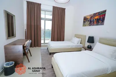 a hotel room with two beds and a desk at Alashrafia Saray 2BR apartment in Sport City in Dubai