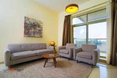 a living room with a couch and two chairs and a window at Alashrafia Saray, Lovely 2 BR apartment in Sport city in Dubai