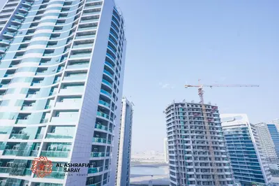 a tall building with a crane on top of it at Alasharafia Saray, Spacious 1BR apartment in Sport City in Dubai