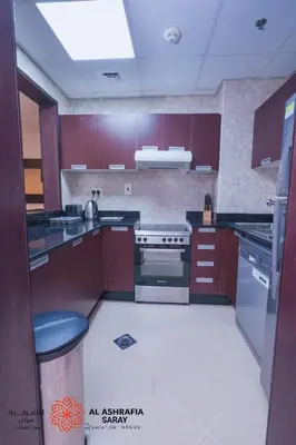a large kitchen with wooden cabinets and a stove at Alasharafia Saray, Spacious 1BR apartment in Sport City in Dubai