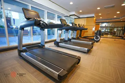 a gym with three tread machines in a room at Alasharafia Saray, Spacious 1BR apartment in Sport City in Dubai