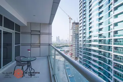 a balcony with a table and a view of a city at Alasharafia Saray, Spacious 1BR apartment in Sport City in Dubai