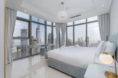a bedroom with a white bed and large windows at La Dolce Vita Residence by Suiteable Interiors in Dubai