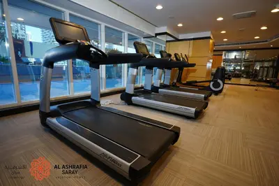 a gym with several tread machines in a room at Alashrafia Saray, Charming 1BR apartment in Sport City in Dubai