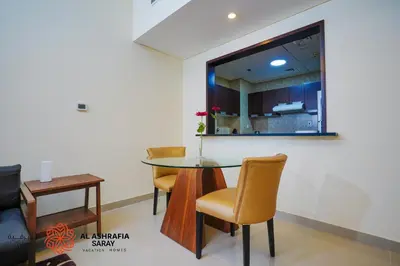 a dining room with a glass table and chairs at Alashrafia Saray, Charming 1BR apartment in Sport City in Dubai