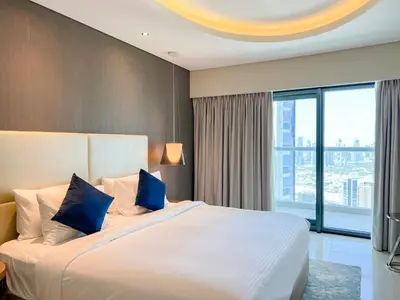 a bedroom with a large white bed with blue pillows at Luton Vacation Homes - Damac Paramount 2BR High Floor, Business Bay, Dubai 61AB06 in Dubai