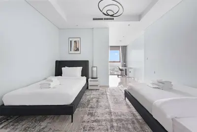 a white room with two beds and a tv at StoneTree - Paramount Tower Hotel & Residences 2 BR - Infinity Pool & Stunning View in Dubai