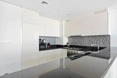a kitchen with white cabinets and a black counter top at StoneTree - Paramount Tower Hotel&Residences 2 BR - Amazing View in Dubai